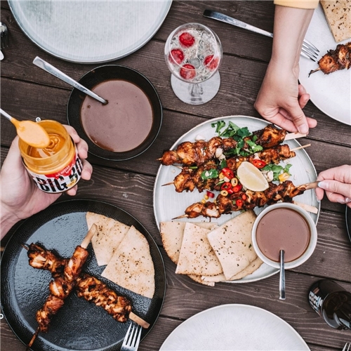 Kuřecí špízy Satay s pita chlebem a arašídovou omáčkou.